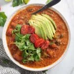 taco soup topped with avocado, cilantro, and tomatoes