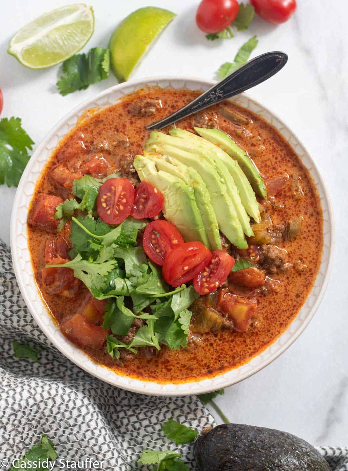 taco soup topped with avocado, cilantro, and tomatoes