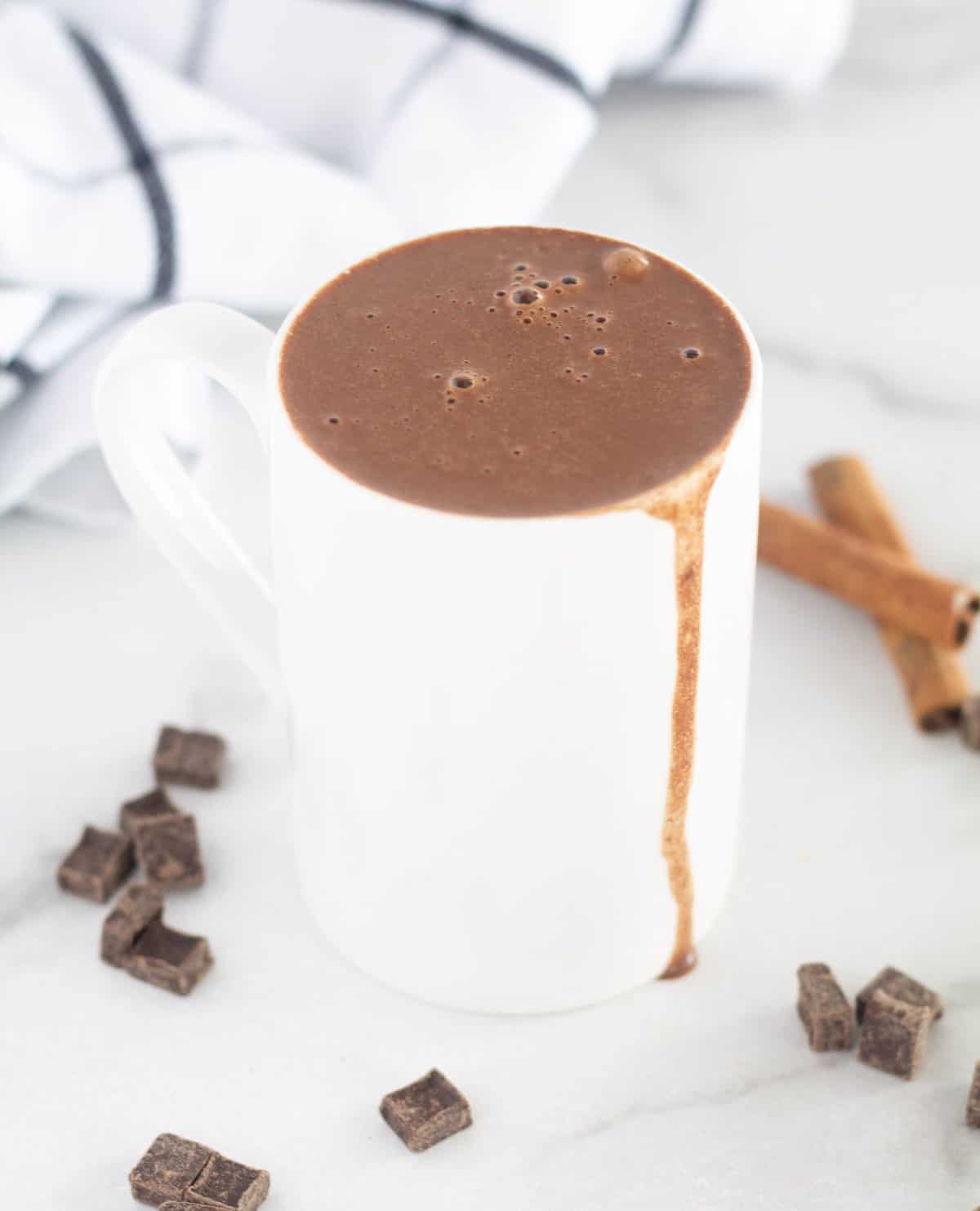 hot chocolate overflowing in white mug with chocolate chips