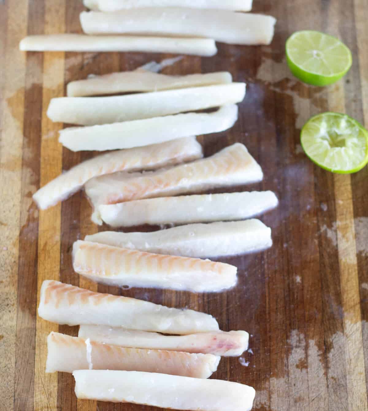 Cut fish on a cutting board with limes