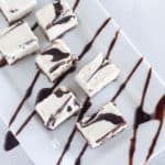 square image of keto cheesecake bites on white plate with chocolate drizzle
