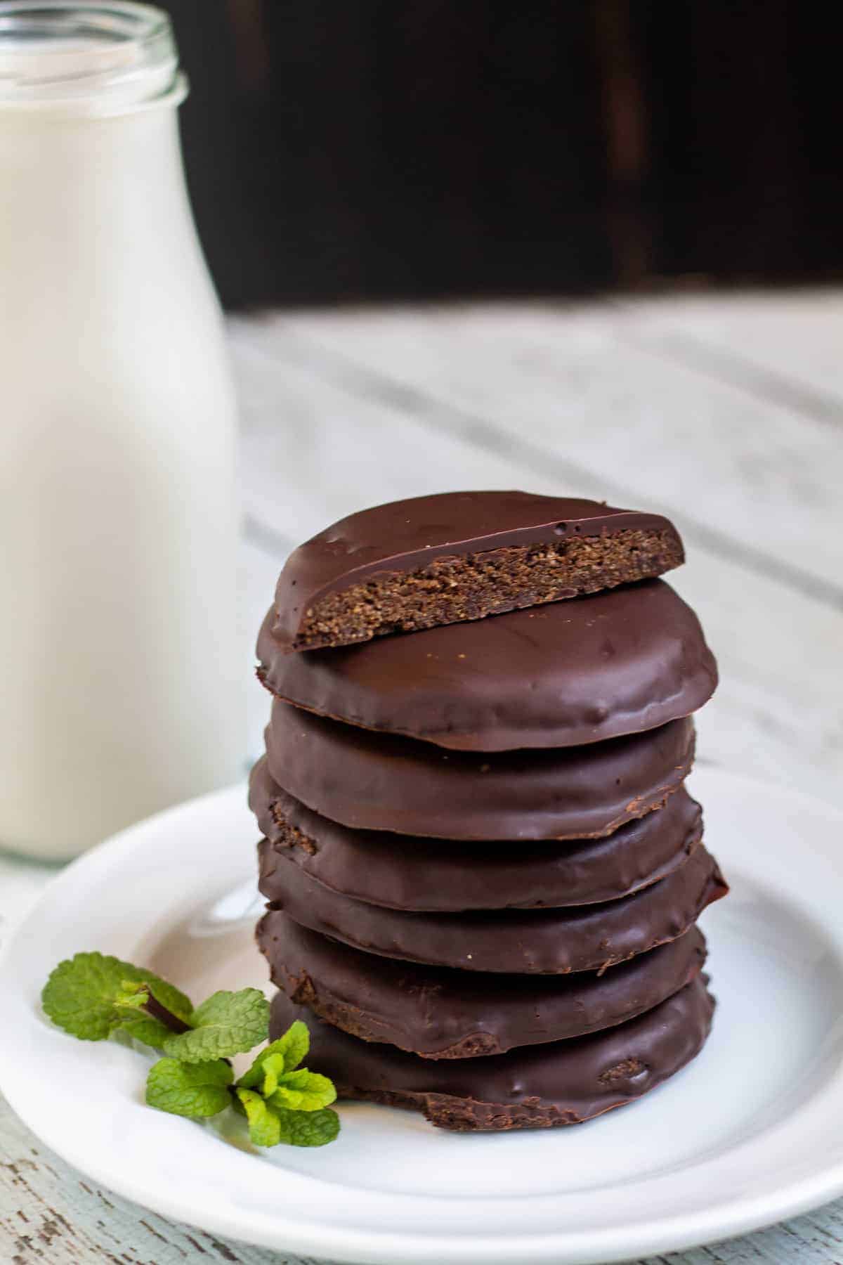 Thin mints stacked on a white plate with milk in the background