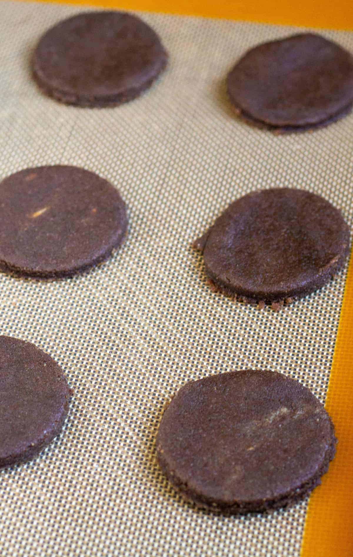 uncooked thin mint wafers on silpat lined baking sheet.