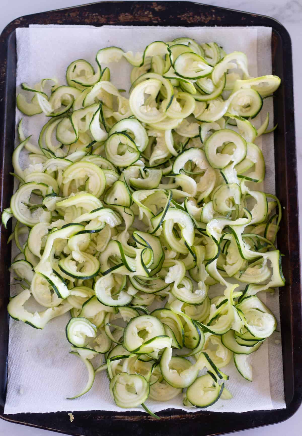 zucchini noodles on paper-towel-lined baking sheet