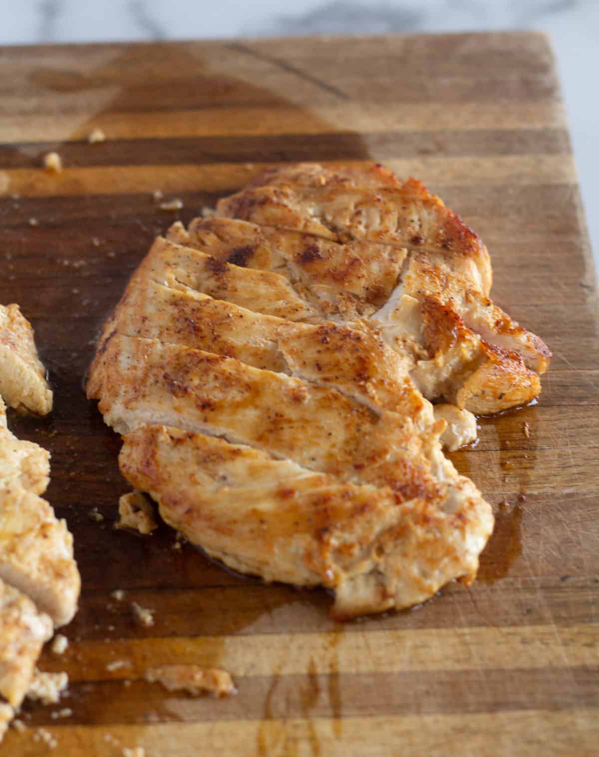 grilled and sliced chicken on cutting board
