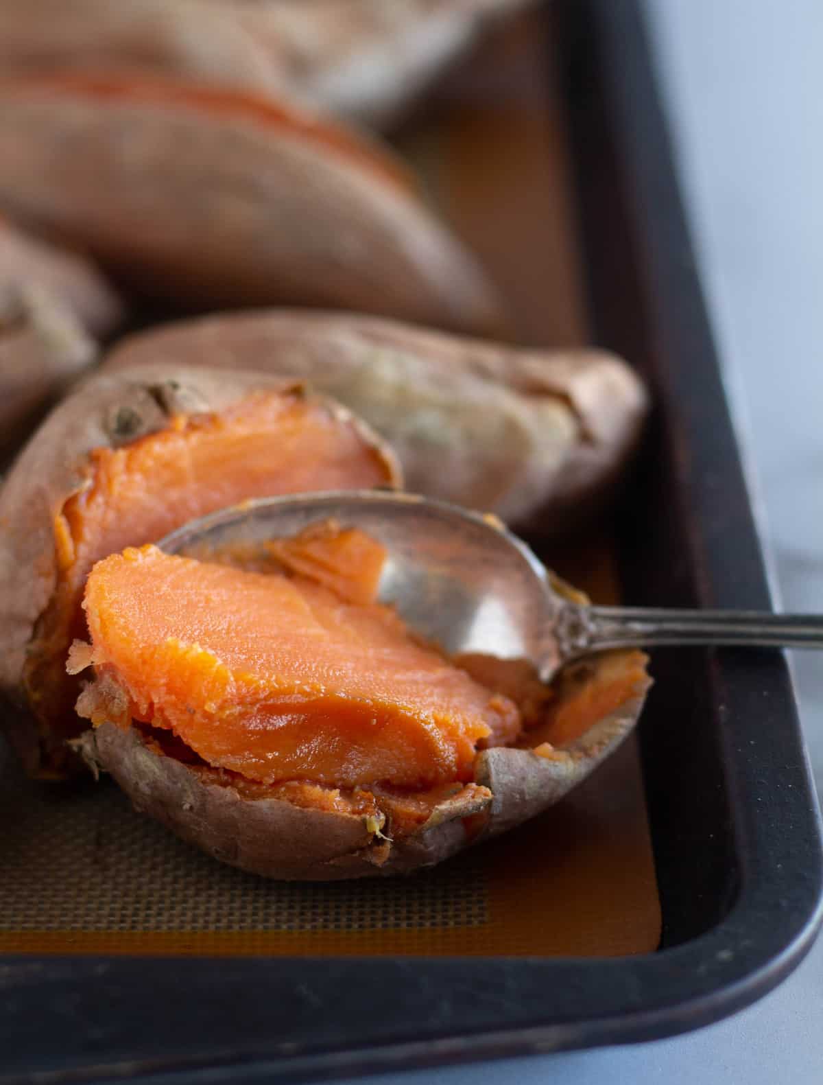 scooping out the flesh of a baked sweet potato