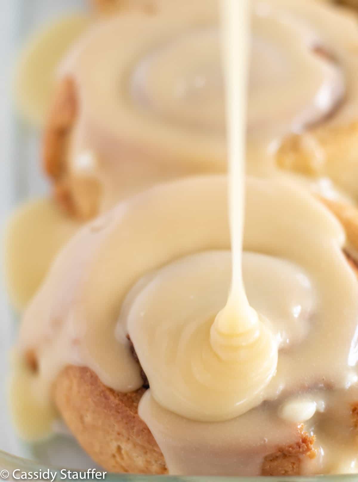 pouring frosting over hot rolls.