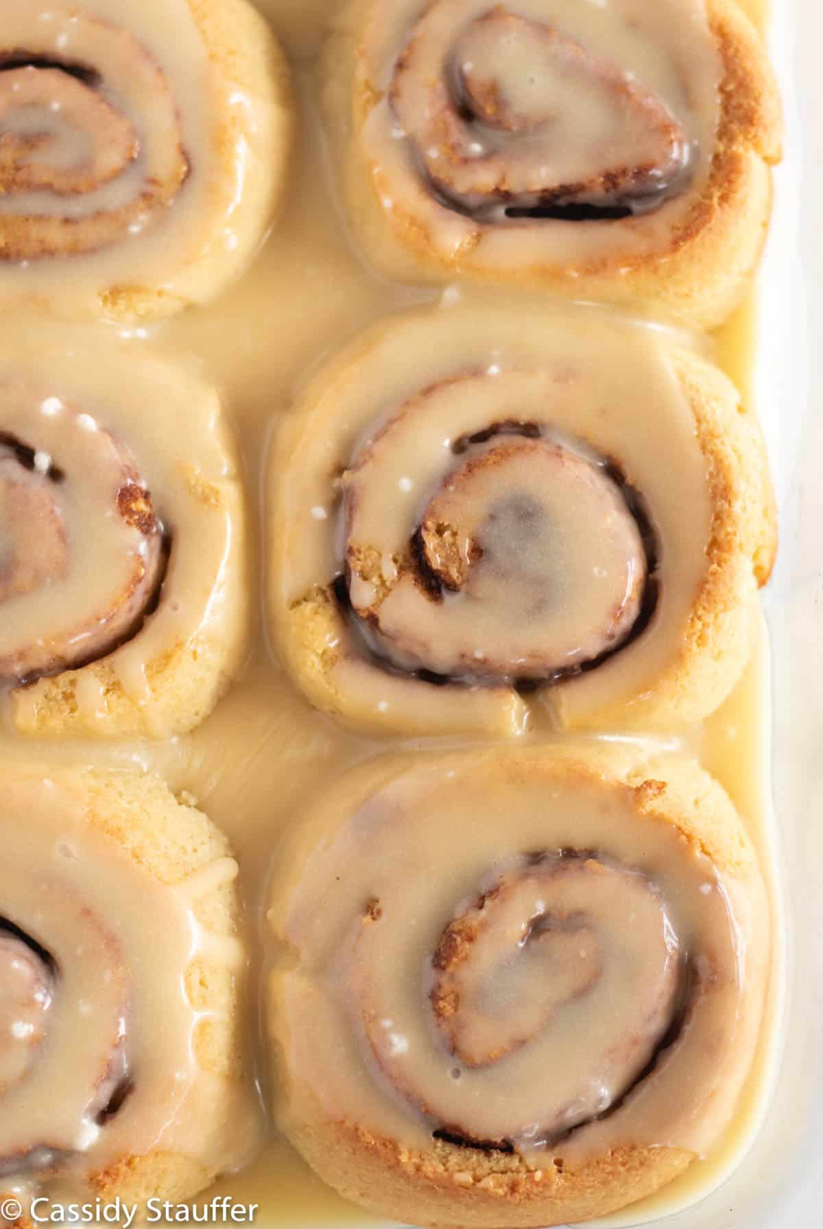 frosted and baked cinnamon rolls in baking dish.
