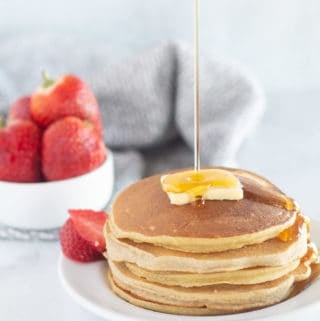 stack of cassava flour pancakes with strawberries and maple syrup