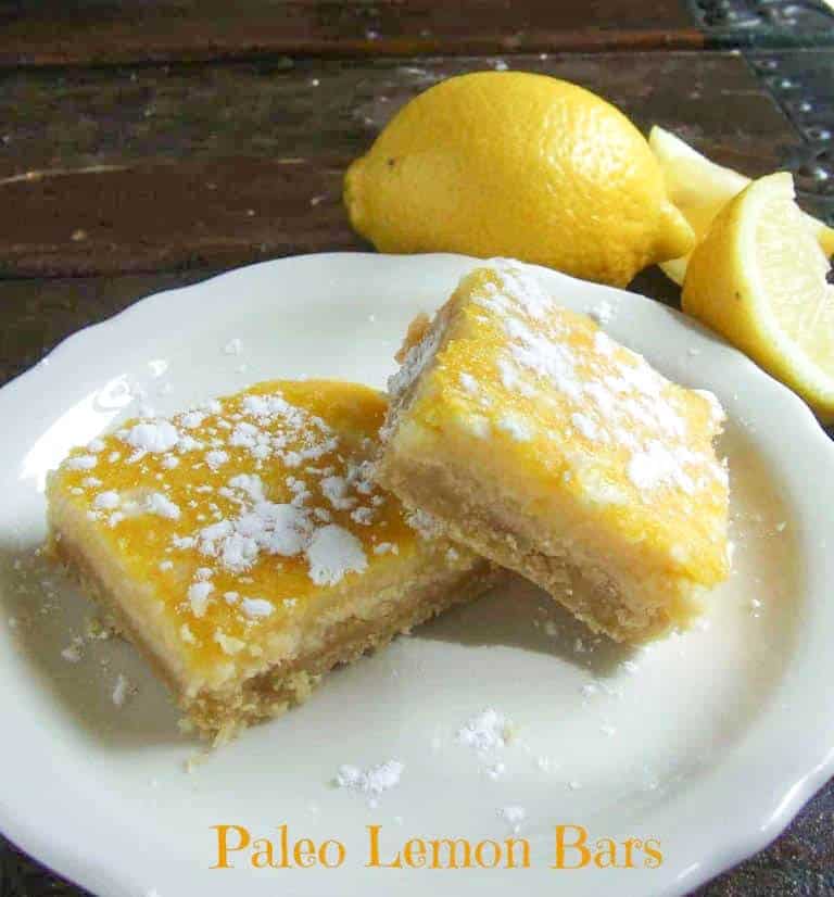 2 paleo lemon bars on white plate with lemons
