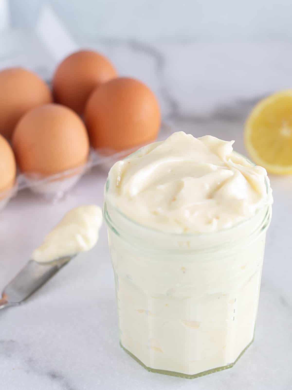 Homemade mayo in small mason jar with ingredients in the background