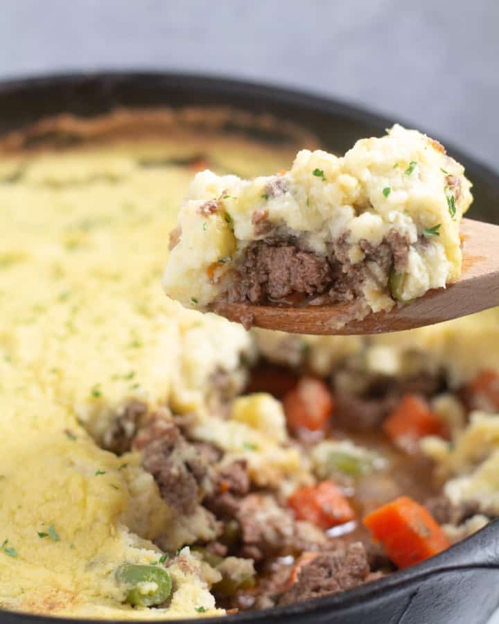 scooping keto shepherd's pie out of a cast iron skillet