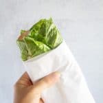 holding up a lettuce wrapped sandwich