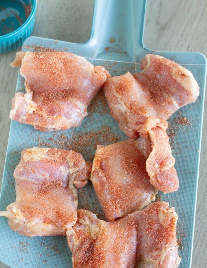 seasoned chicken thighs on teal cutting board