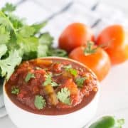 salsa in small white bowl with cilanto and tomatoes