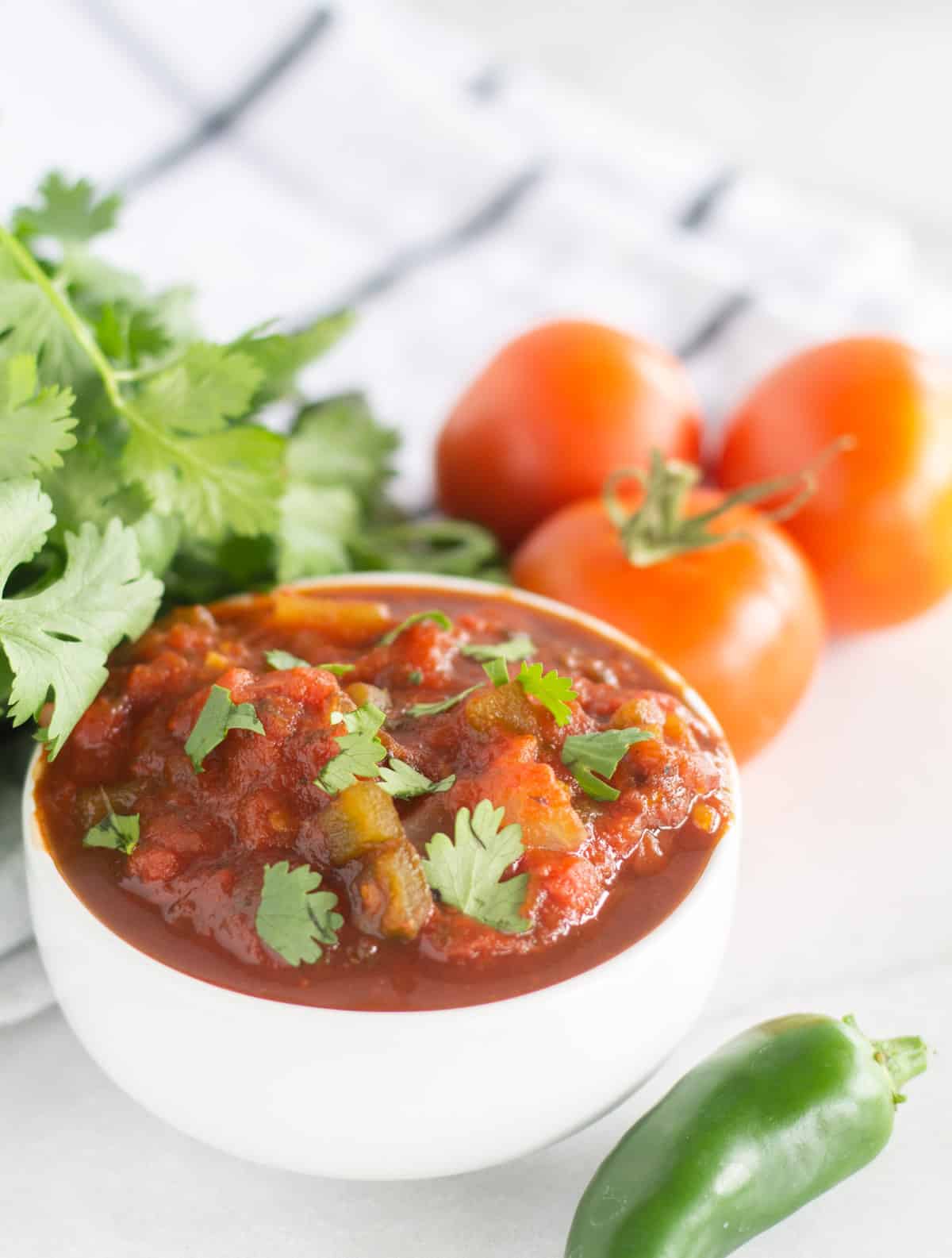 salsa in small white bowl with cilanto and tomatoes