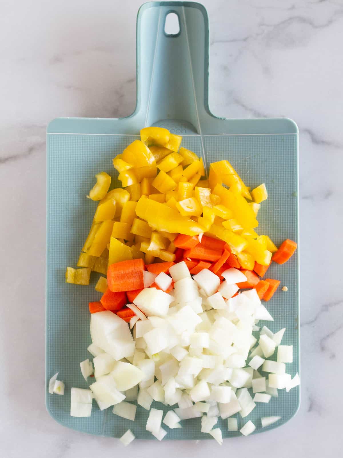 chopped onion, carrot and bell pepper on cutting board