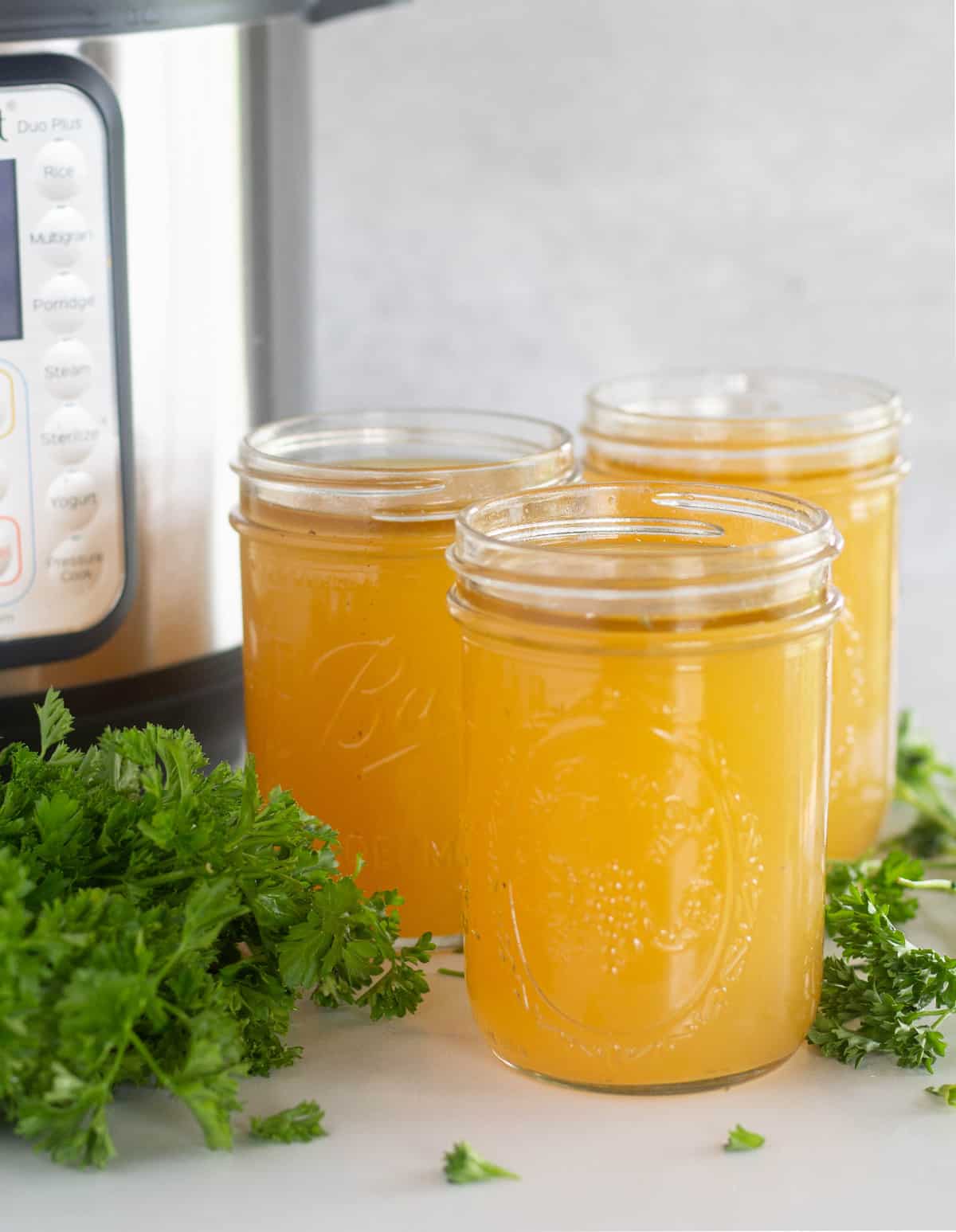 Broth in mason jars with instant pot and parsley in background