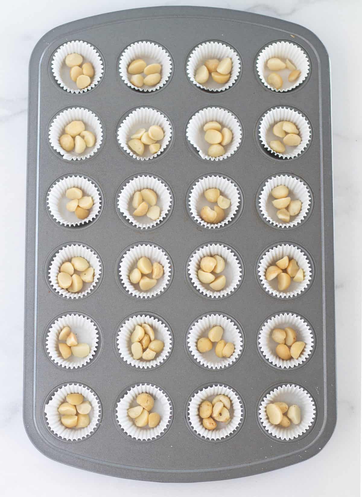 Macadamia nuts in lined mini muffin tin.
