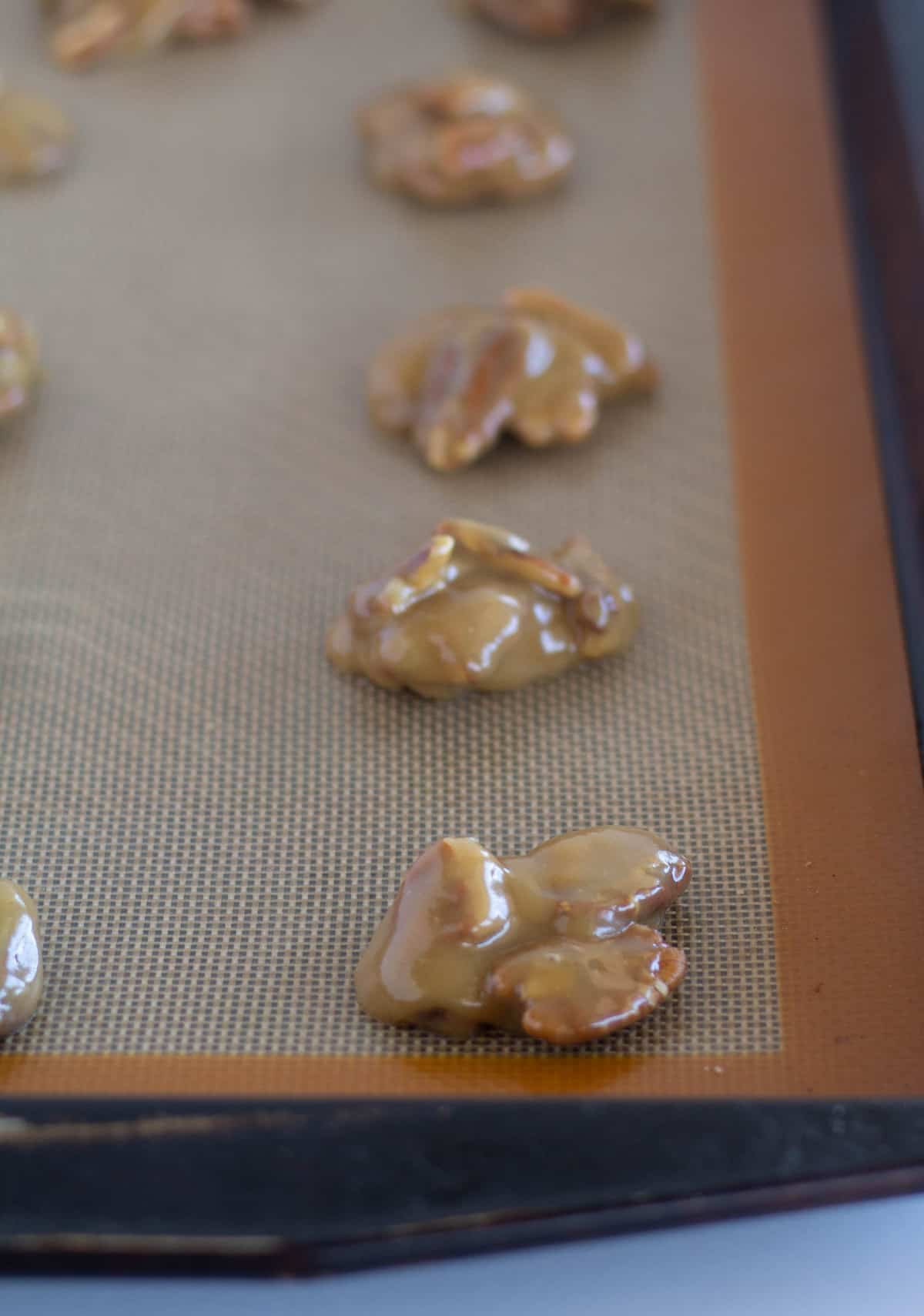 mounds of pecan/caramel mixture on lined baking sheet.