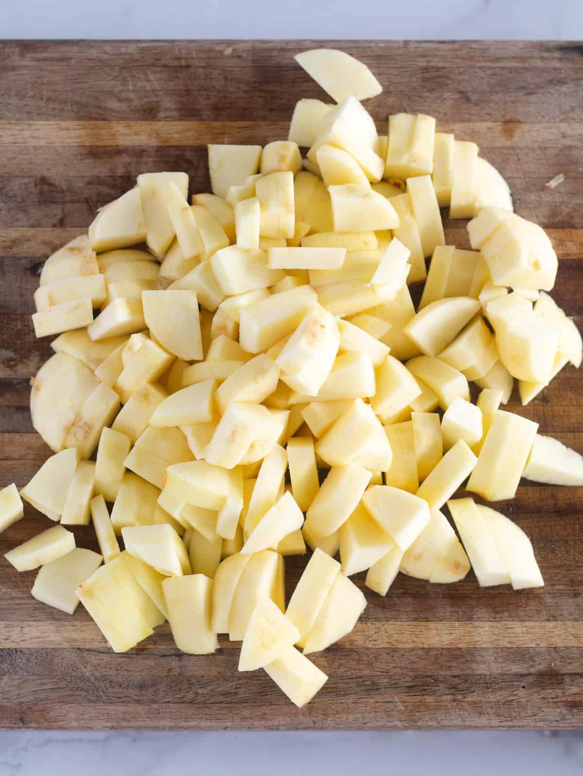 peeled and chopped apples on a wooden cutting board.