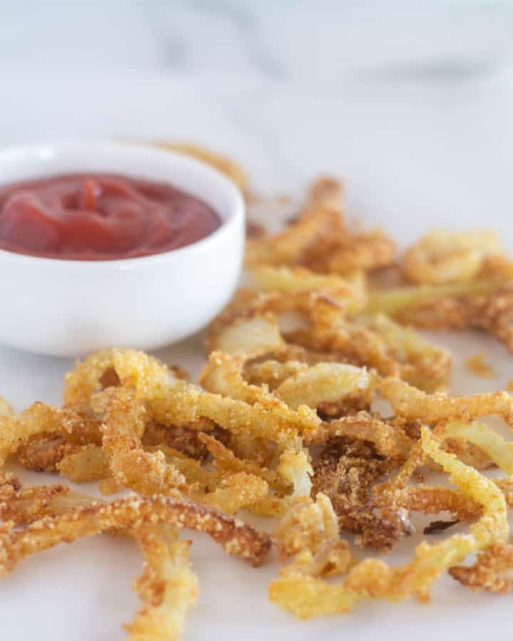 close up of keto fried onions with a small bowl of ketchup