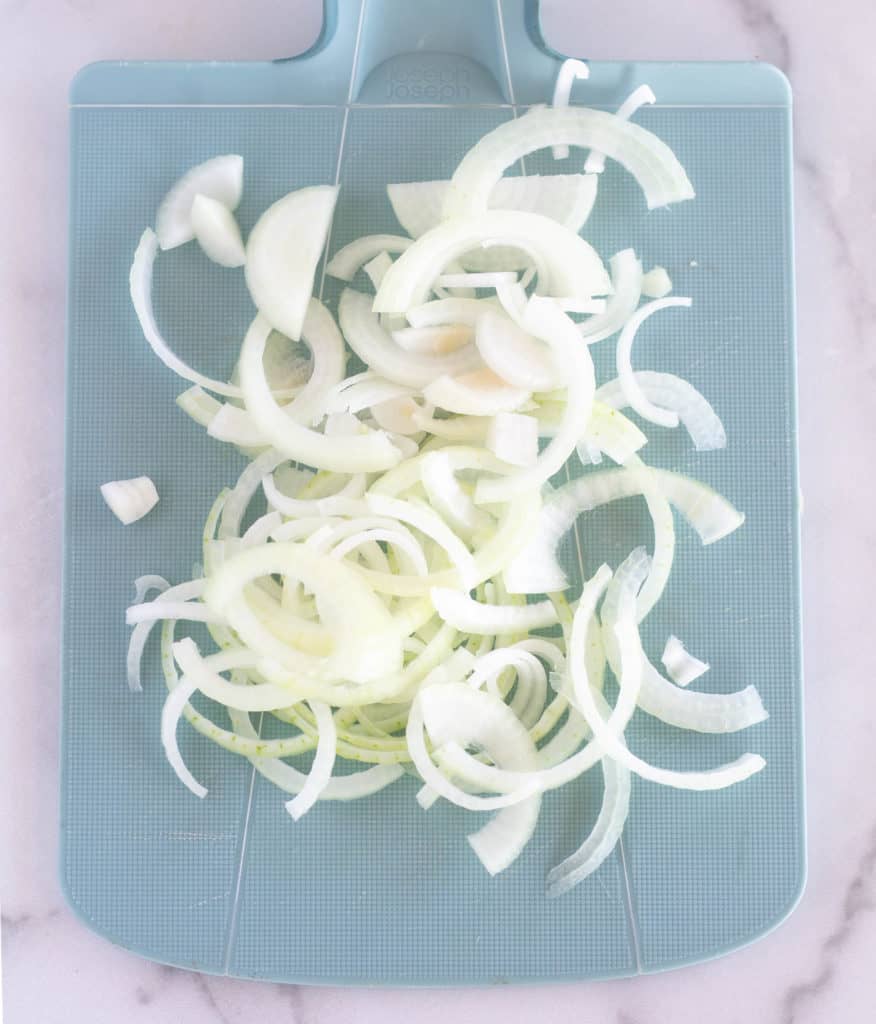 sliced onions on teal cutting board