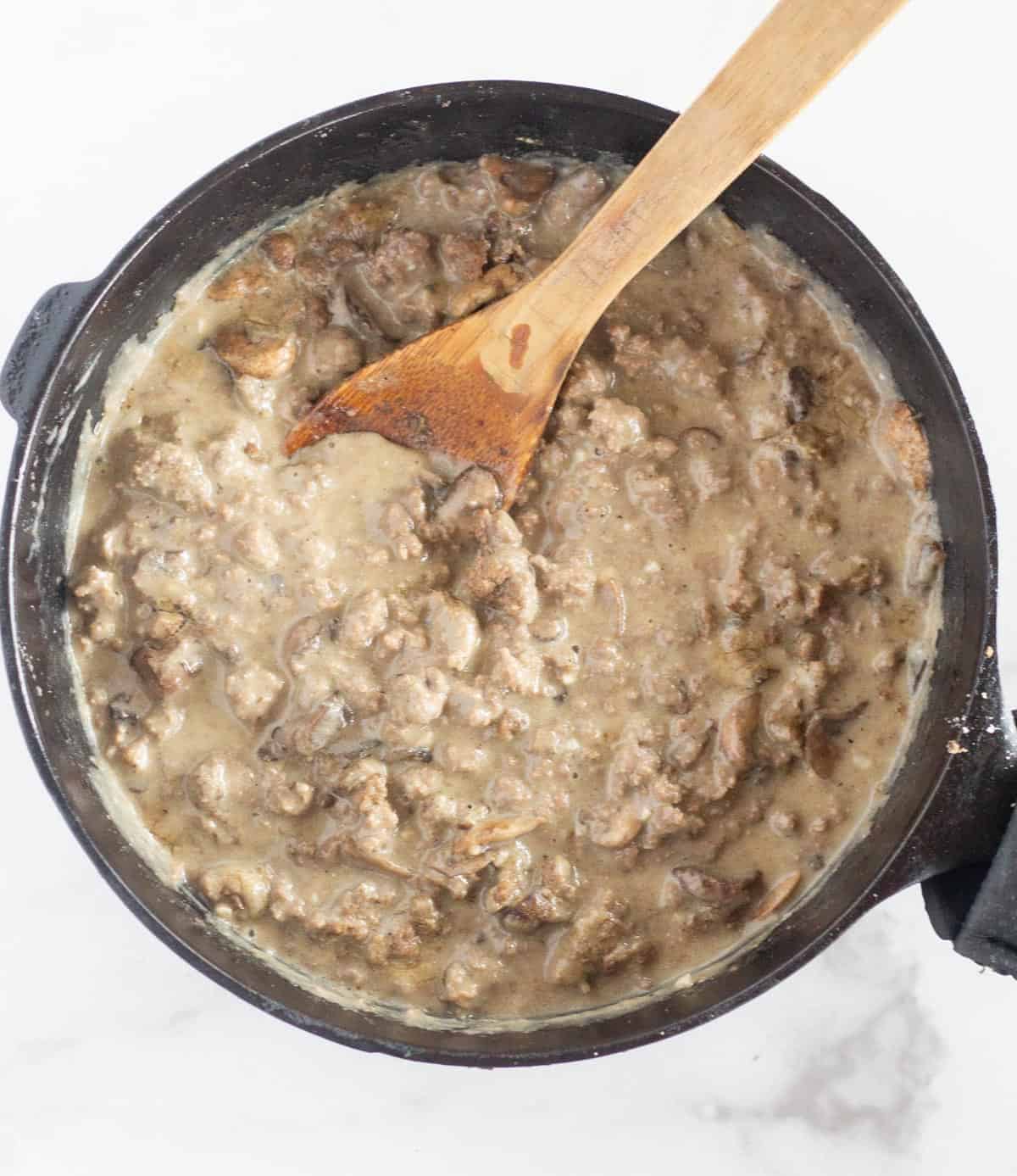 stroganoff in cast iron skillet with wooden spoon
