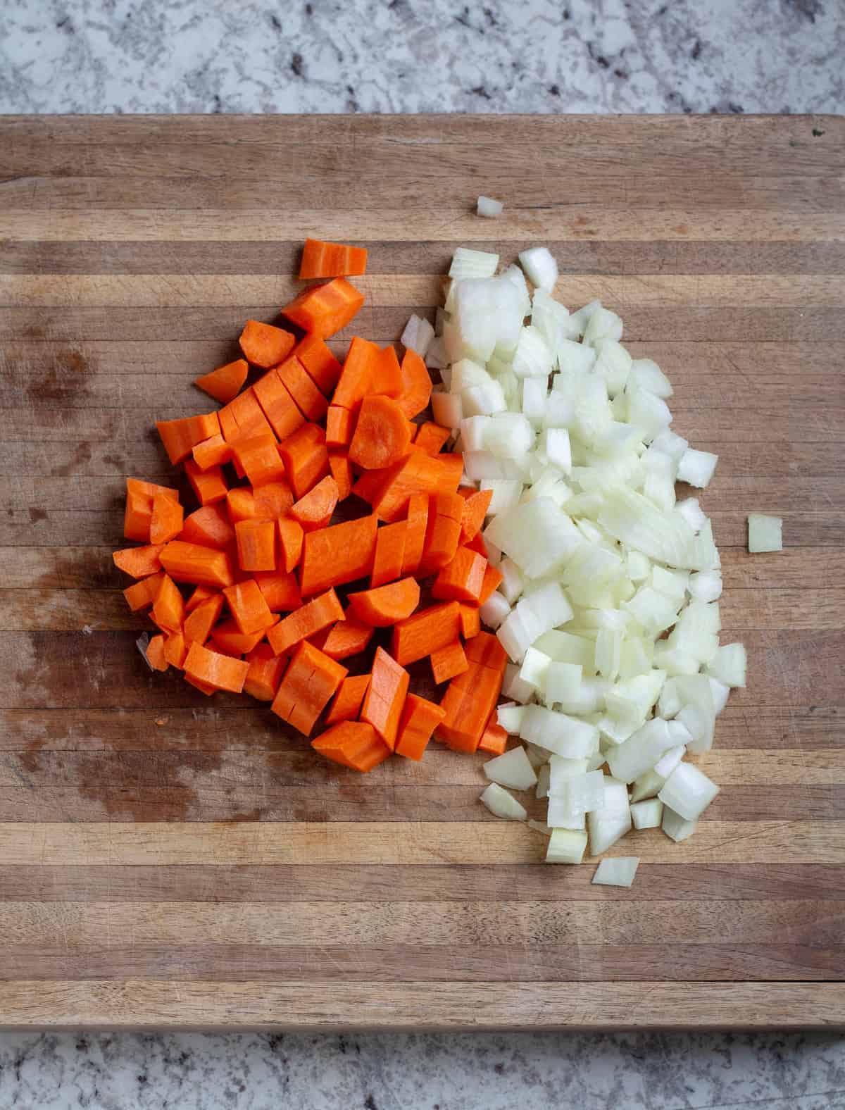 chopped carrots and onions on wooden cutting board