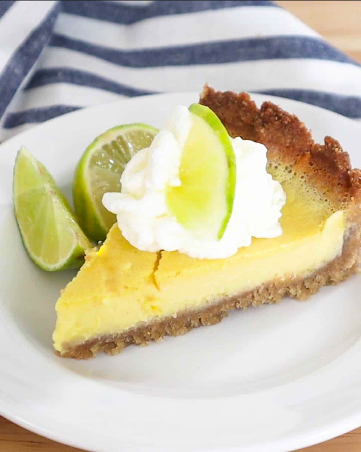 key lime pie on a plate with whipped cream and limes