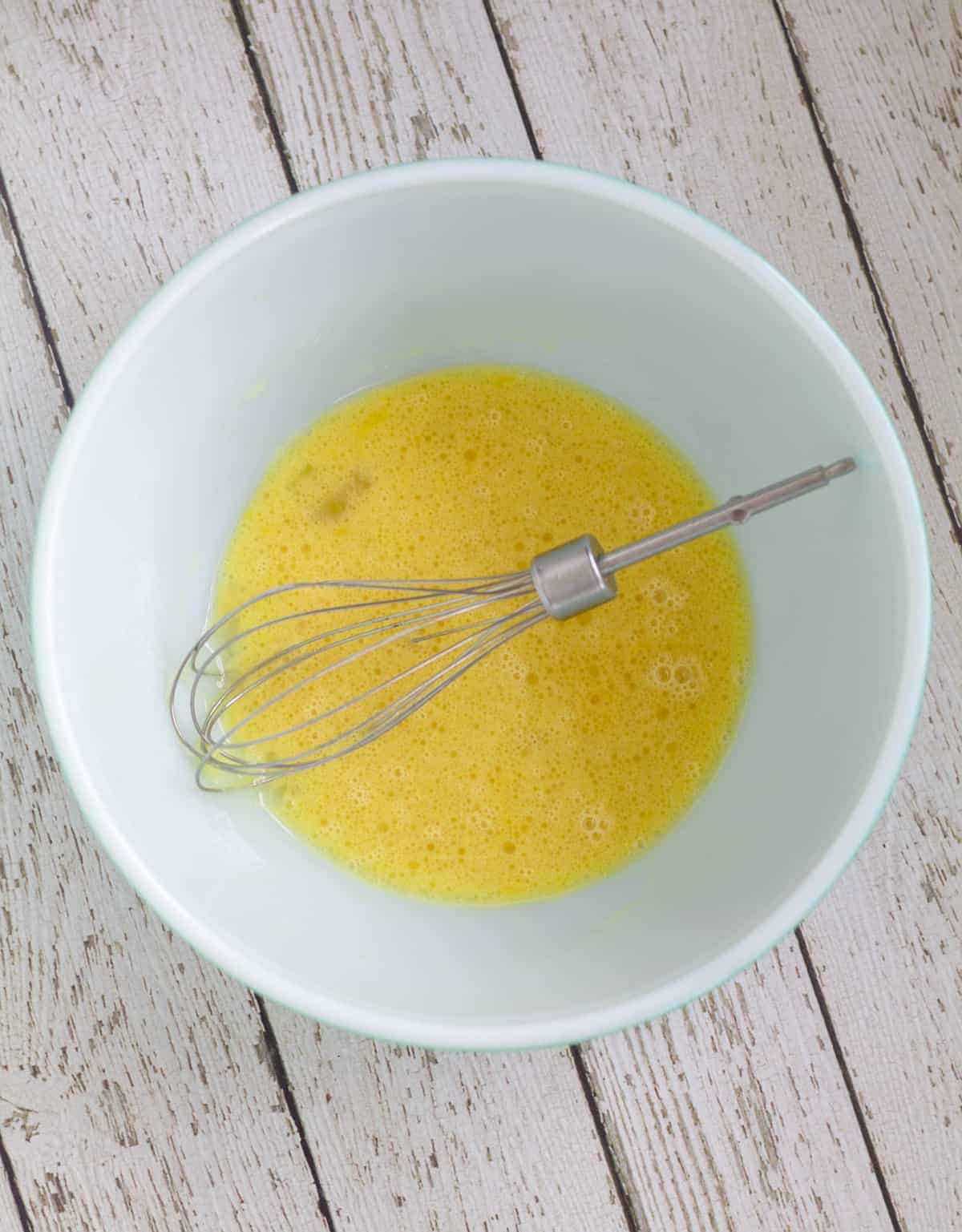 Eggs and wet ingredients whisked together in white bowl