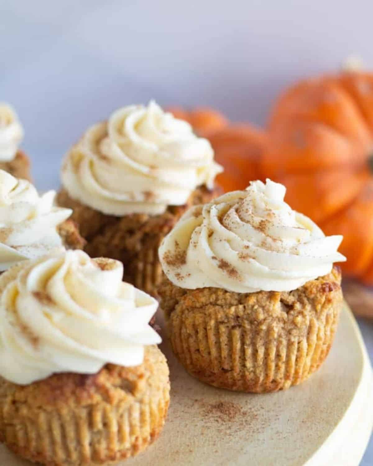 pumpkin cupcakes on wooden cake plate.