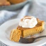 slice of pumpkin pie on plate with bite on fork