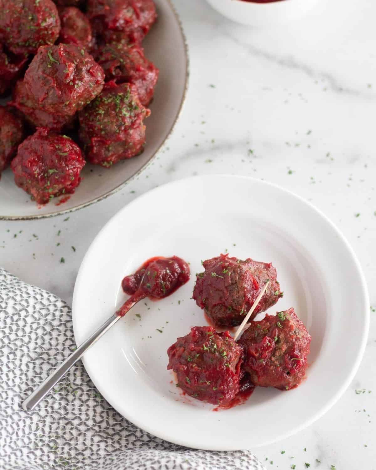 3 meatballs with small spoon on white plate