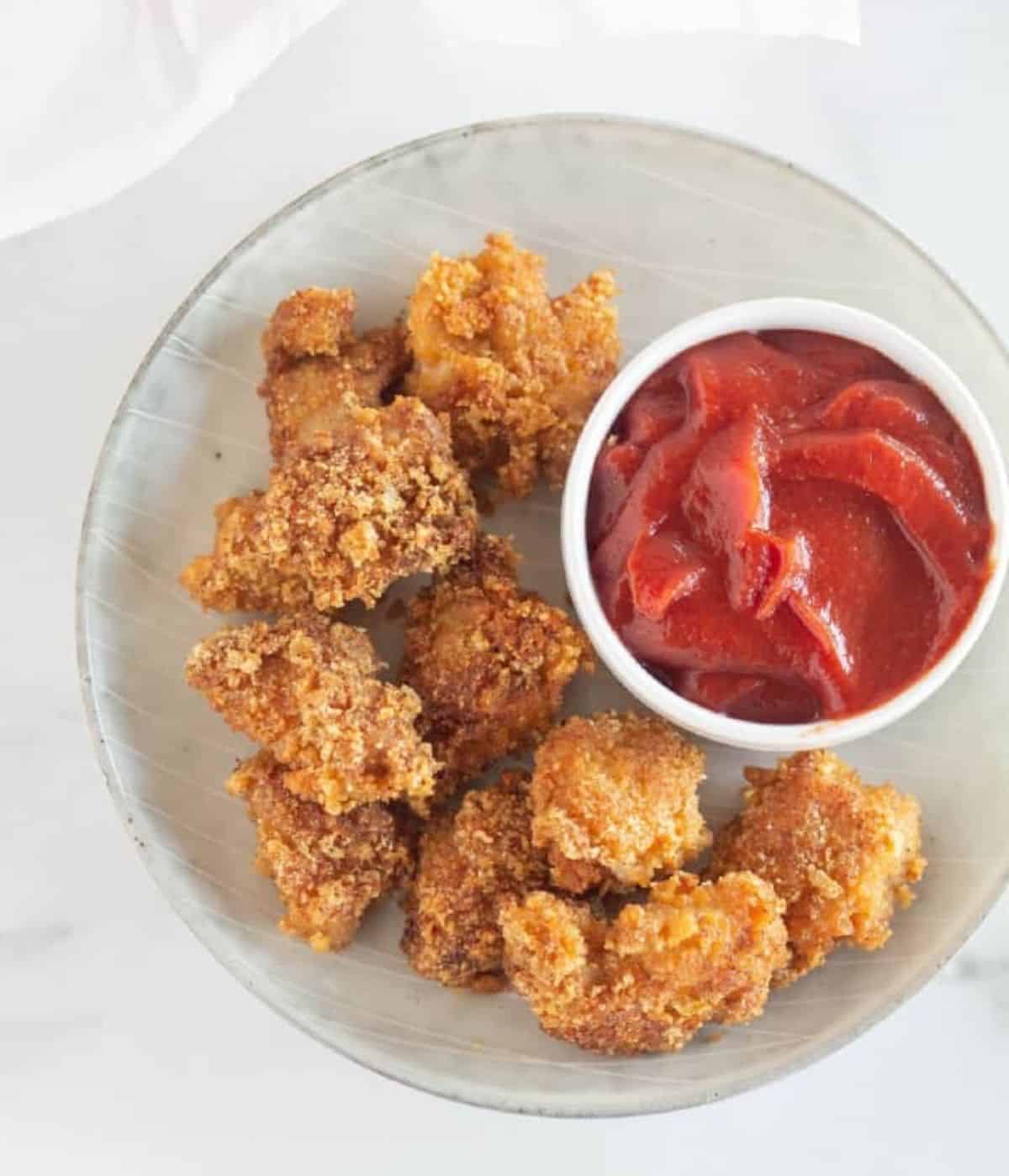 chicken nuggets on plate with ketchup.