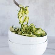 scooping zoodles with fork out of white bowl