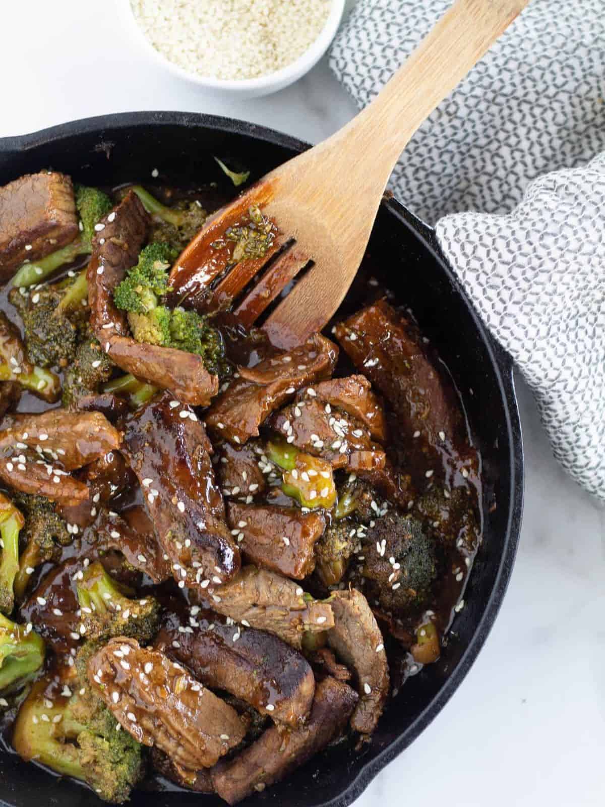 Finished low-carb broccoli beef in a cast-iron skillet with sesame seeds.