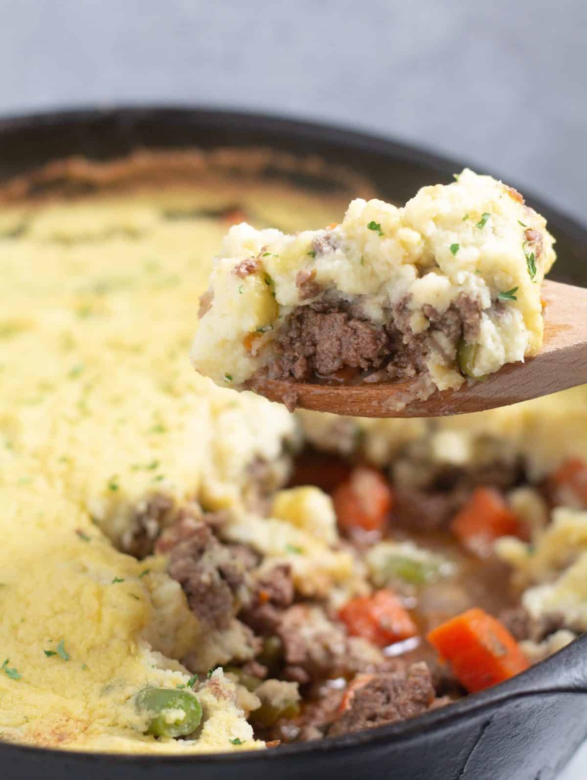 scooping shepherds pie out of a cast iron skillet