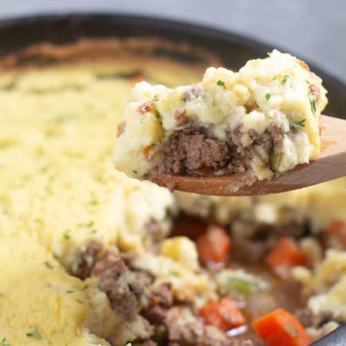 scooping out keto shepherds pie from a cast iron skillet