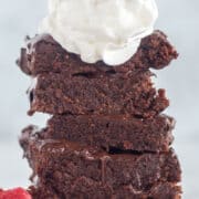 stacked brownies with whipped cream and raspberries.