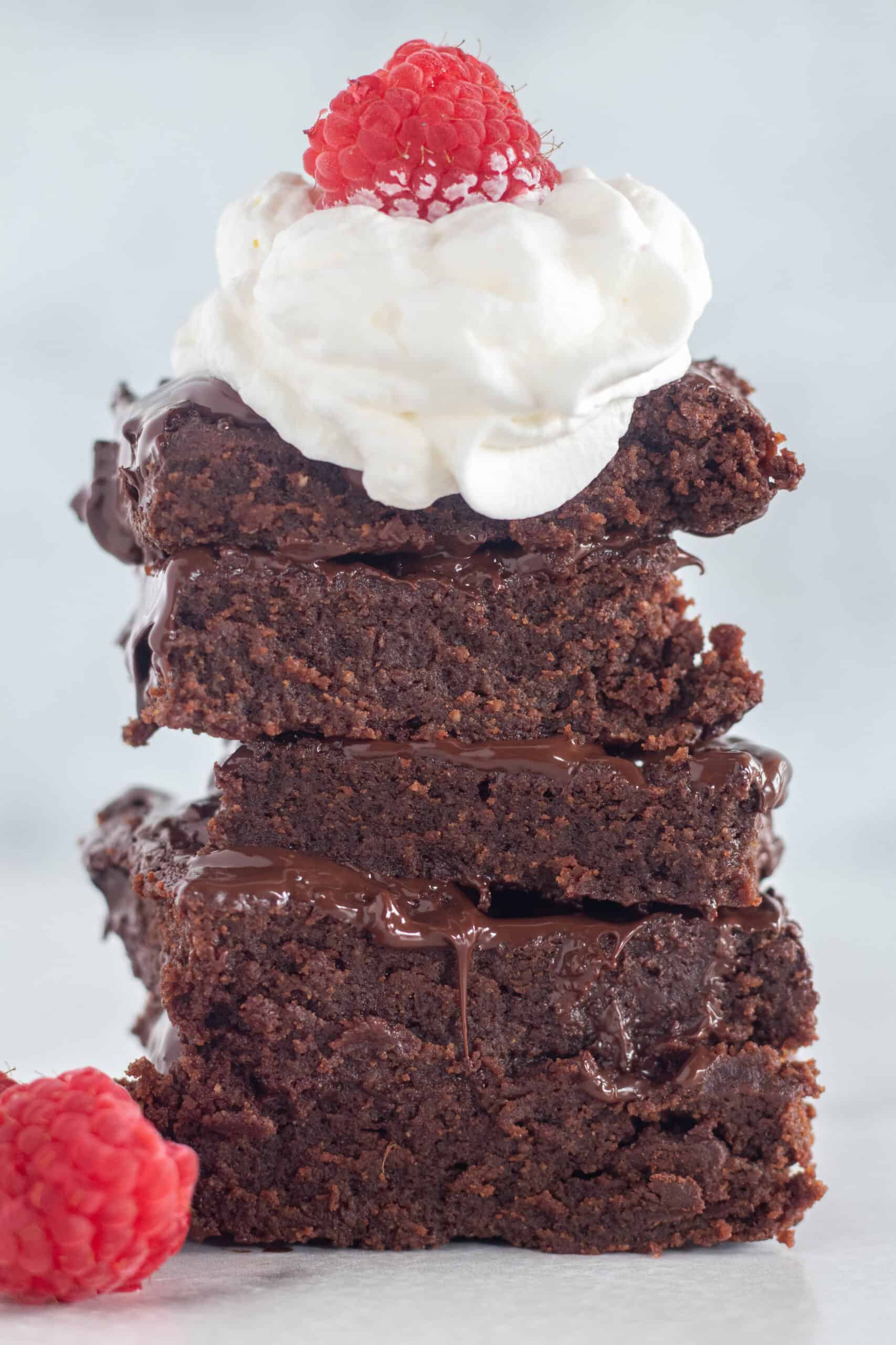 stacked brownies with whipped cream and raspberries.
