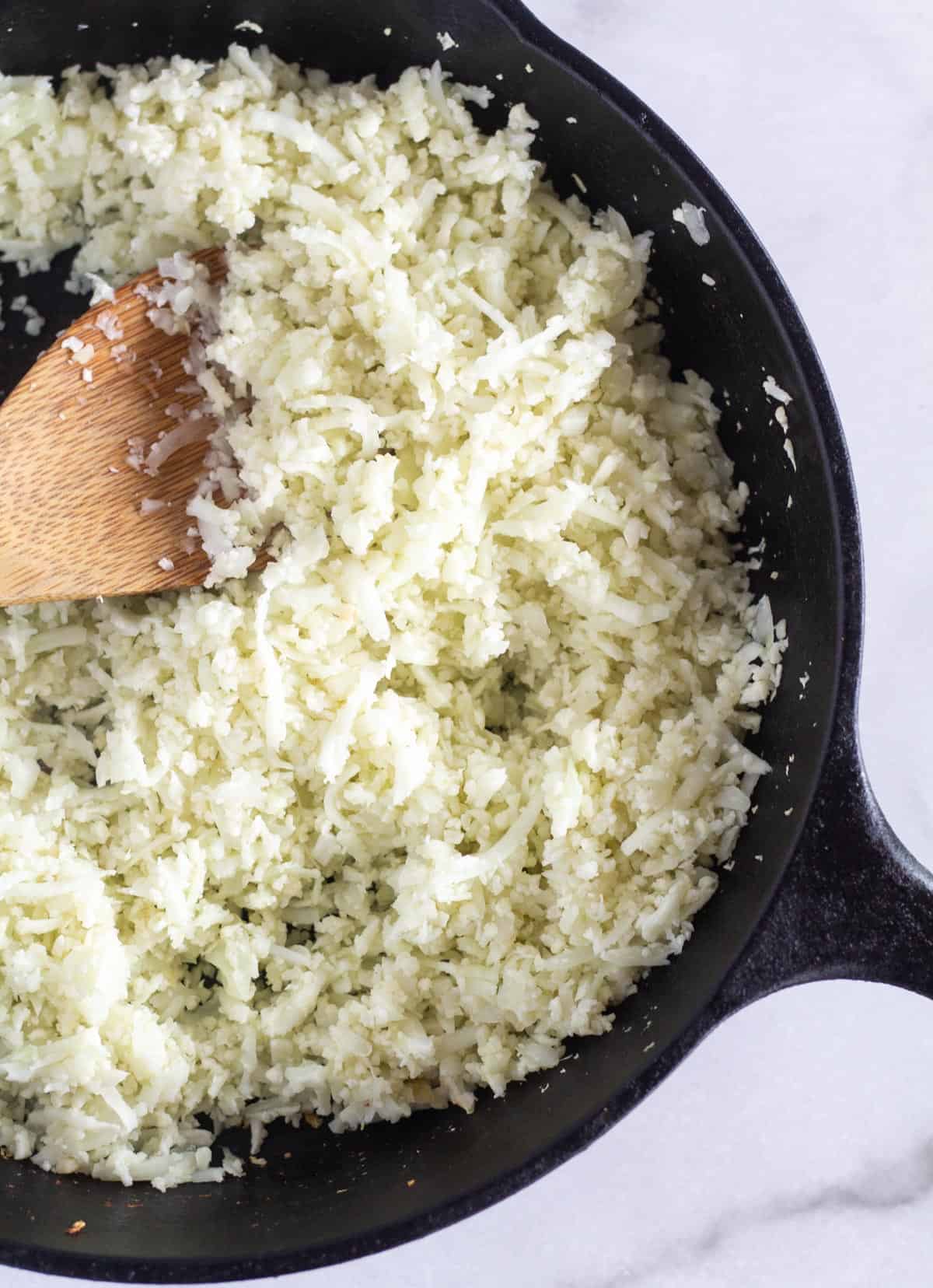 cooked cauli rice in cast iron skillet.