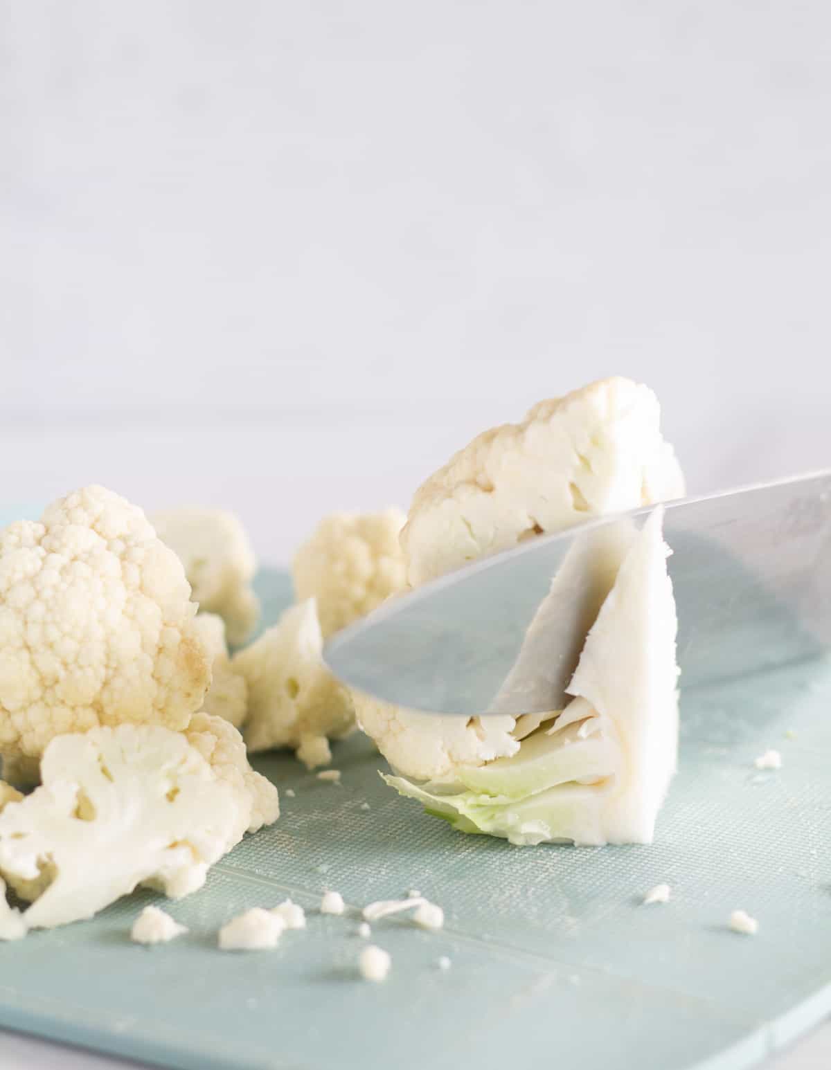 cutting the core of a piece of cauliflower.