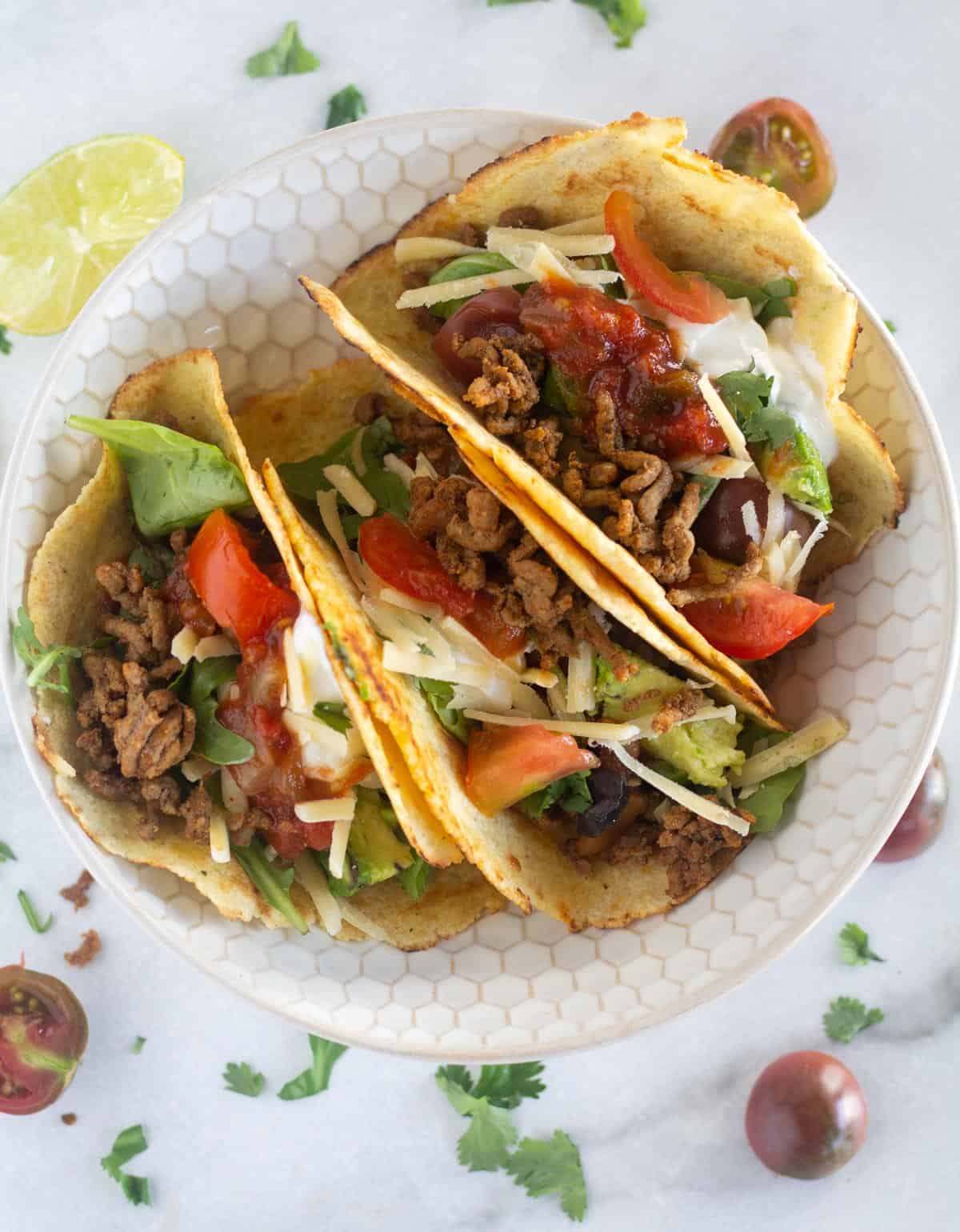 3 tacos on a small plate with garnishes