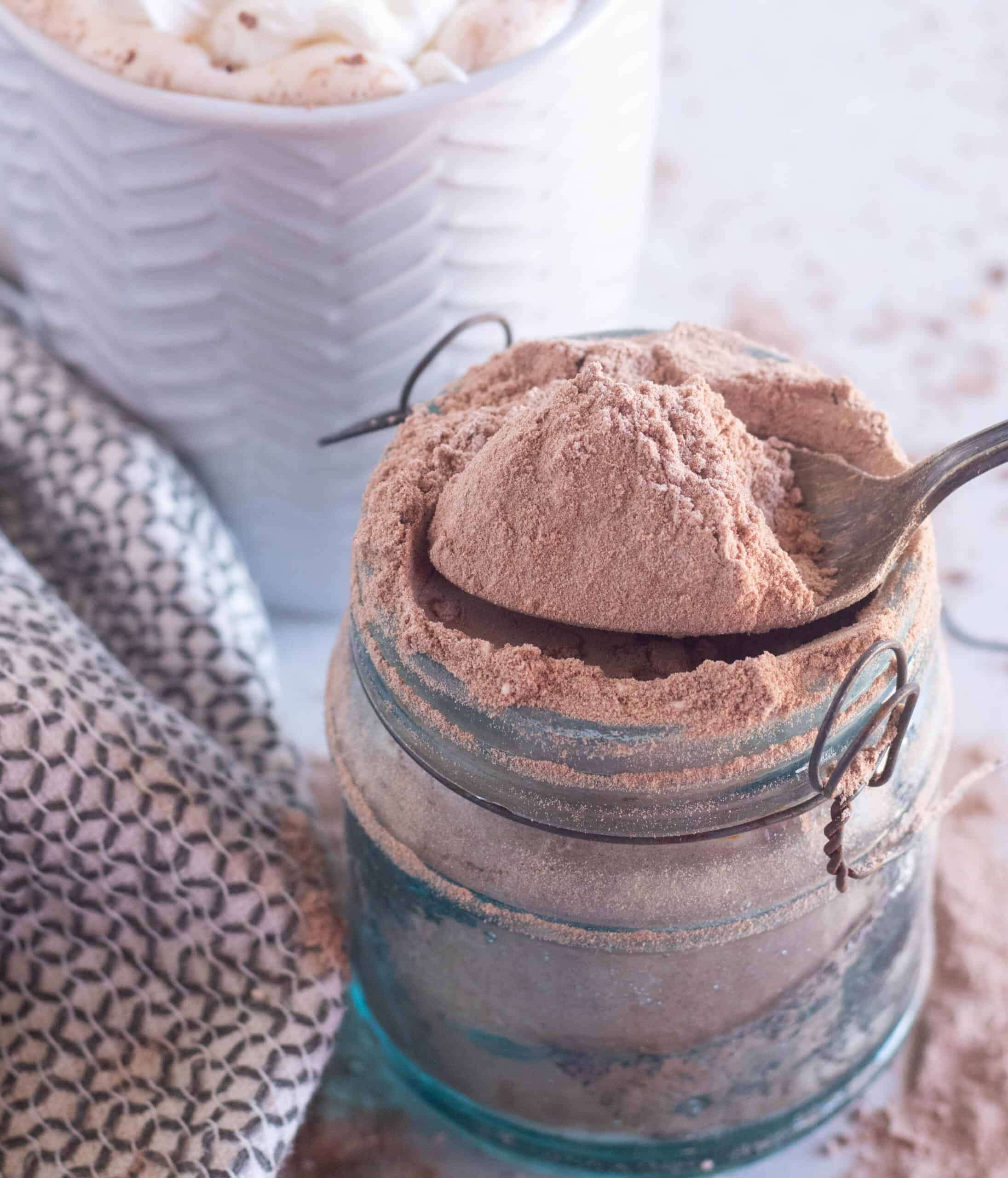 scooping hot chocolate mix out of a glass jar.