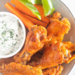 chicken wings on a plate with ranch and veggies
