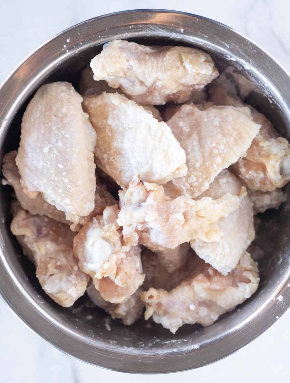 wings coated in baking powder in a large bowl