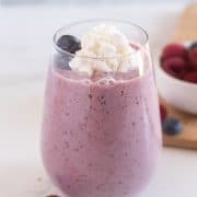 berry smoothie garnished with whipped cream and fresh berries