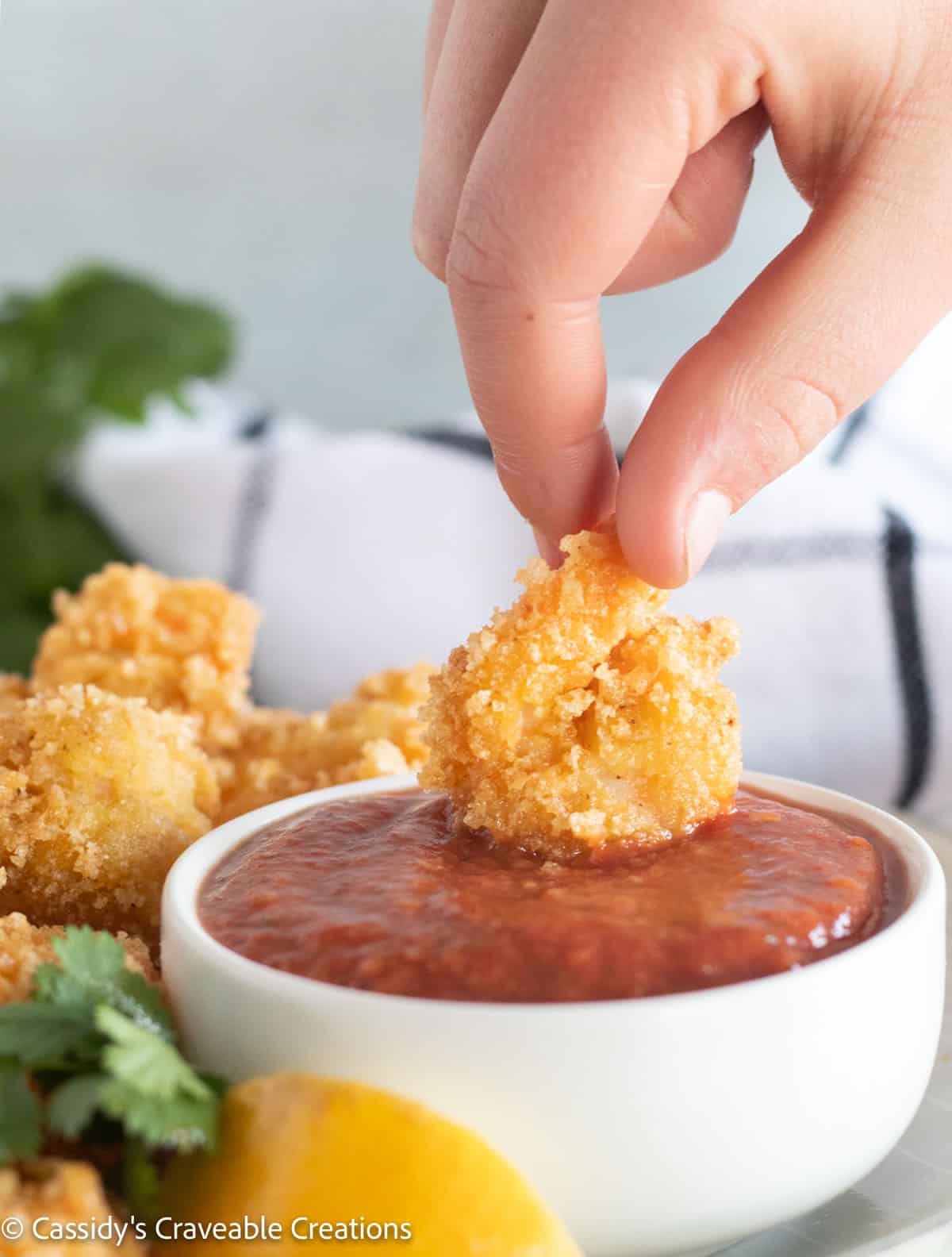 dipping fried shrimp into cocktail sauce.