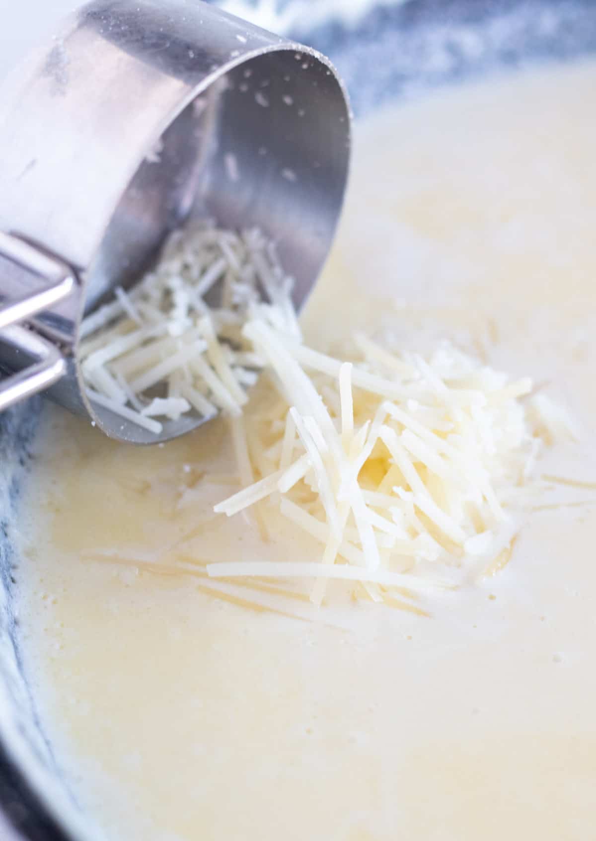 adding grated parmesan to alfredo